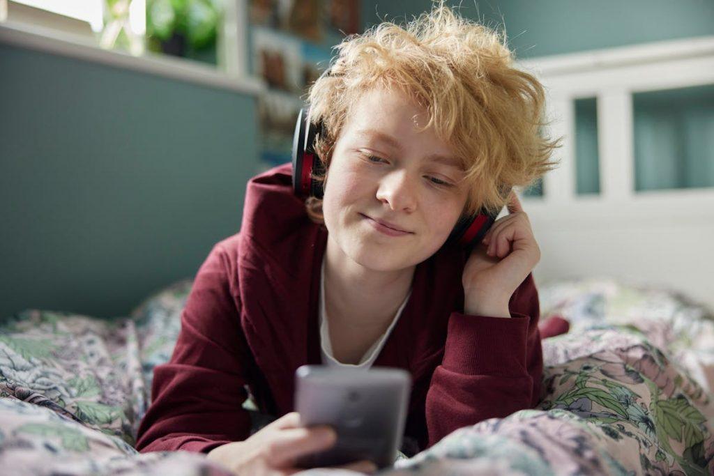 A young adolescent using a smartphone with headphones, illustrating typical phone use among youth relevant to nomophobia and phone addiction