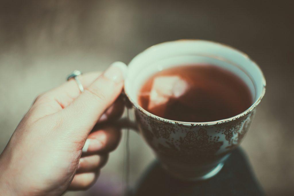 gros plan sur une tasse d’infusion chaude, lumière dorée, vapeur douce.