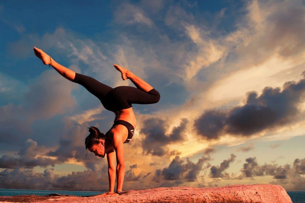 personne faisant du yoga sur un tapis beige, lumière du matin.