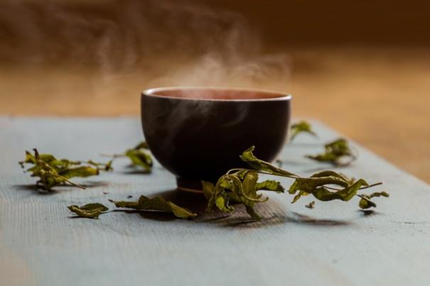 tasse d’infusion fumante sur une table en bois, lumière douce du matin.